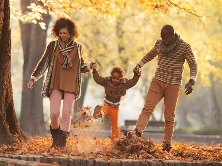 Family walking holding hands kicking leaves